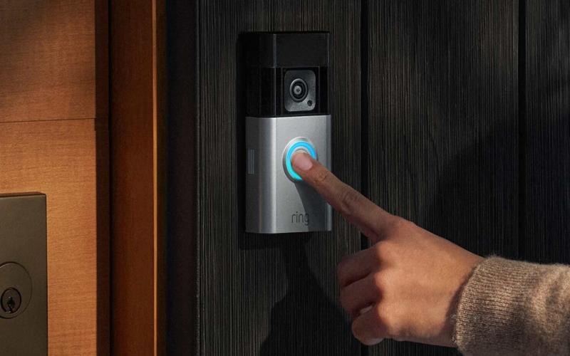 Person mounting a Ring Battery Doorbell Plus on a front door during installation steps